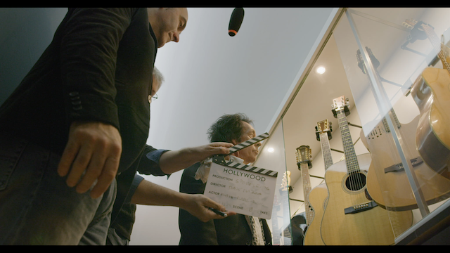 Ciak della scena 37 Alessandro Gallo accompagna Robin Le Mesurier nella scelta della chitarra